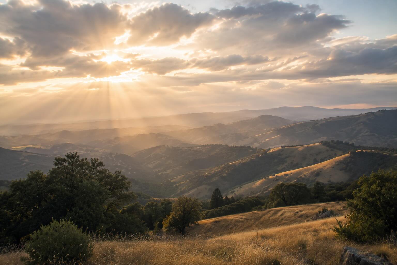 Soft morning light breaking through clouds over California hills