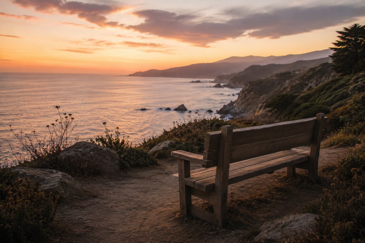 A wooden bench overlooking the California coast at dusk